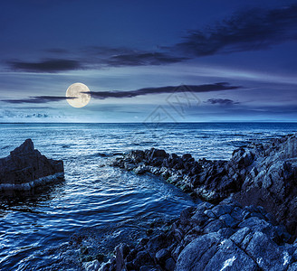 夜晚在满月的光照下在海边岩石海岸上漫着巨石图片