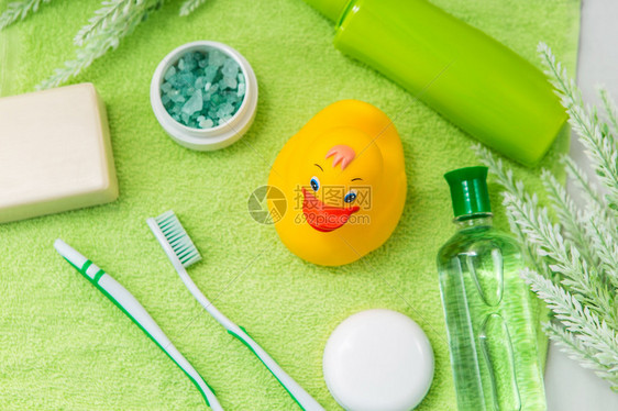 绿色毛巾上的浴室配件橡皮鸭牙刷海盐肥皂和乳液沐浴的婴儿护理配件孩子们的图片