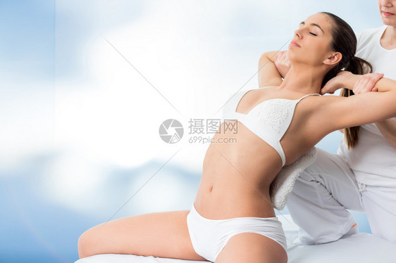 与物理治疗师进行脊柱治疗的年轻有魅力的女人的特写治疗师用膝盖沿脊柱图片