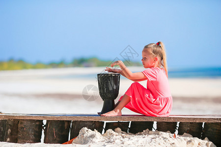 快乐的小孩女在海滩咖啡馆玩得开心在奇异图片