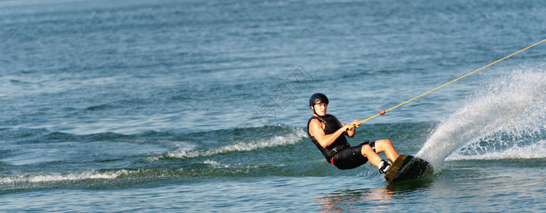 极限运动Wakeboarder享受在湖上骑行和切割水面的乐趣背景