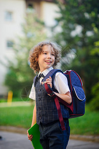 小学生们站在校园里小学生打扮得体在男孩的书包后面一年级学生移开视线图片