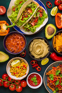 混合墨西哥食物派对食物木桌上的鳄梨酱玉米片法吉塔肉炸玉米饼莎酱辣椒西红柿顶视图德墨美食各种开胃菜图片