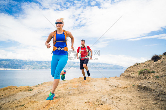 几个跑步者背着包在海边和山区的岩石小径上跑步图片
