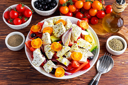 希腊沙拉配新鲜甜椒红洋葱橙樱桃番茄黄瓜黑橄榄和羊奶酪背景图片
