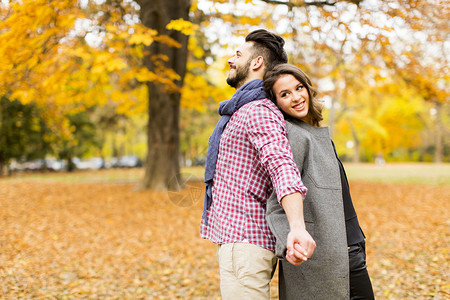 在秋季公园合影的年轻夫妇背景图片
