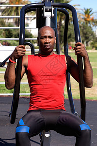 在公共园内使用运动设备进行锻炼的非洲年轻男图片