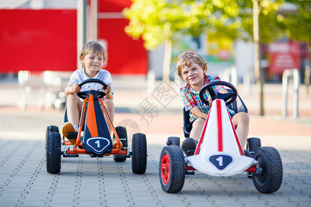 两个活跃的小男孩在夏天户外驾驶踏板赛车背景图片