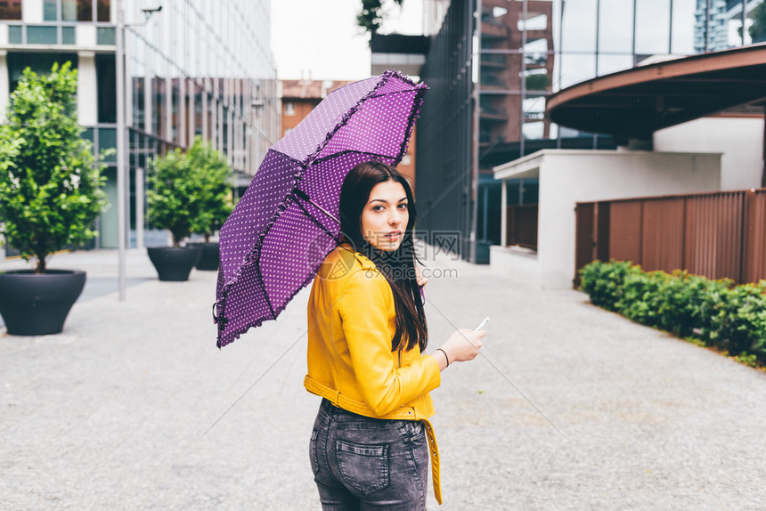 在雨天拿着伞在城里户外散步的长直发女图片