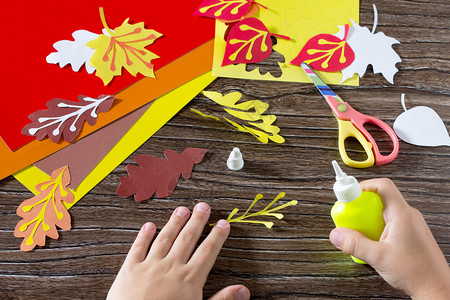 秋天的彩色纸叶在木制背景上孩子被粘纸叶子孩子们的纸工艺品图片