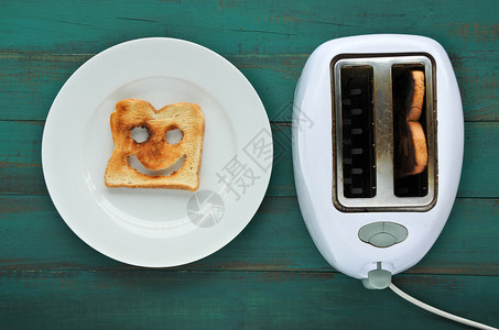 在烤面包机旁边的盘子里放一片吐司面包的平躺视图幸福的概图片