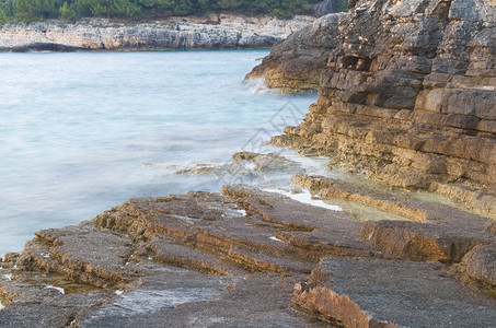 蓝色波浪海和棕色岩石海岸长时间曝光图片