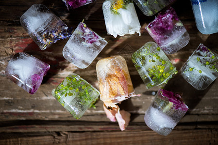 RusticWooden背景的冰晶立方体中的冻结花图片