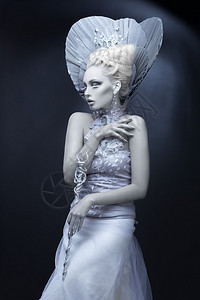 打扮成冬皇后的年轻美女的肖像创意化的妆品在黑暗背景高清图片