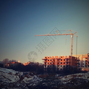 起重机和新建筑的建造日落时建筑业背景图片