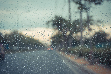 汽车挡风玻璃和雨滴在路面背景下以图片