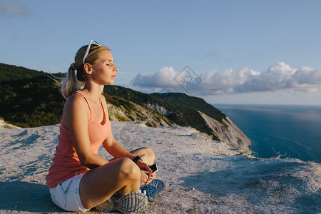 年轻女子在山顶悬崖和海边背景山顶上户外做瑜伽莲花图片