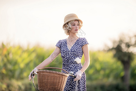 1930年代时尚的金发美女穿着蓝色夏装在农村地貌图片