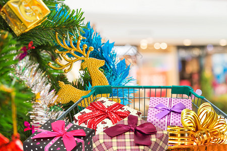 圣诞礼物和礼物盒在购物车购物车与圣诞树和模糊的图片