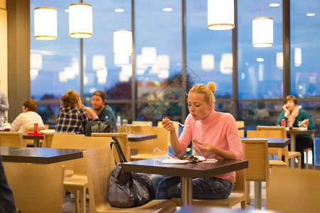 年轻女旅行者在机场餐厅吃披萨图片