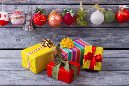 用彩色纸包裹的圣诞礼物圣诞球挂在木制背景上的绳子上家庭图片