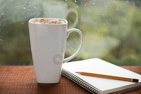 一杯加棉花糖的咖啡和一张雨天窗口图片