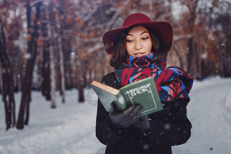 在冬季中持有红帽子和读诗书的年轻图片