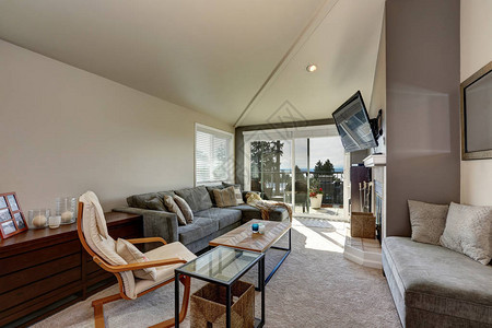 西雅图公寓的客厅内部房间里有高的拱形天花板灰色沙发和壁挂式电视也有通往阳台的出口图片