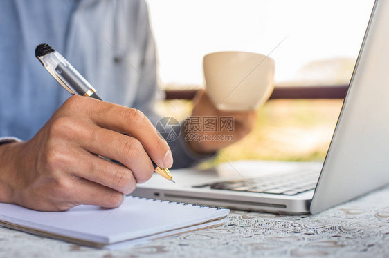 商人使用笔记本电脑在咖啡馆用笔记本写字图片