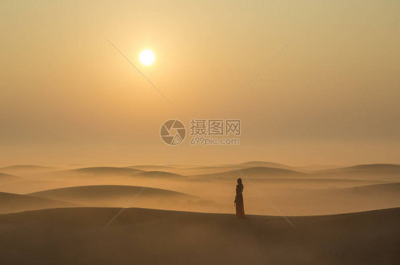 在阿联酋迪拜附近日出时站在沙丘中迷雾中站立图片