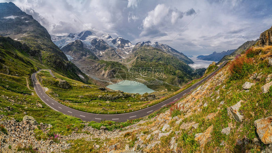 摩托车手在阿尔卑斯山蜿蜒的山口公路上行驶图片