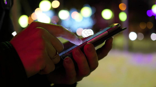 男人在城市晚上使用智能手机上的应用程序发送短信图片