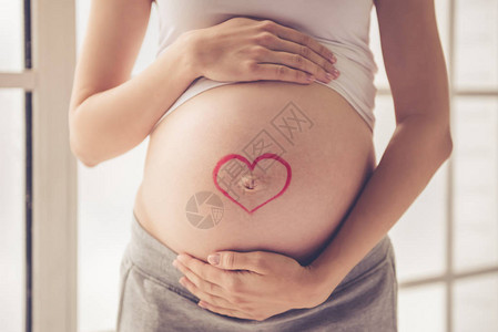 美丽的孕妇拥抱她的肚子的裁剪图像图片