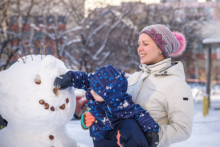 小孩男在美丽的冬日让雪人户外做雪人图片