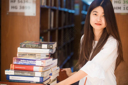 一个年轻有魅力的亚洲女人在图书馆坐着看书的画图片