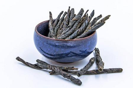 Kudin冬青苦丁茶的扭曲叶子在白色隔绝的蓝色陶瓷碗的苦图片
