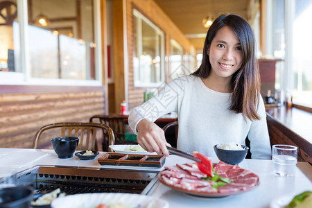 在日本餐厅吃烤肉的女人背景图片