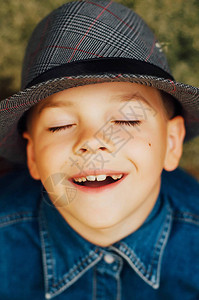 孩子开心的脸一个可爱的孩子的肖像金色短发和棕色的小男孩美丽的小男孩七岁戴着帽子和牛仔衬衫合影图片