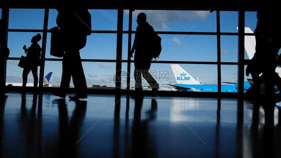 携带手提箱和行李在机场旅行的旅客步行前往窗前启程轮图片