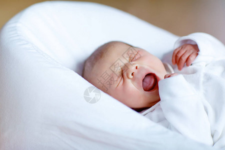 可爱的新生婴儿在白床上哭泣图片