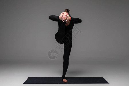 美丽的瑜伽女在灰色背景下练习瑜伽图片
