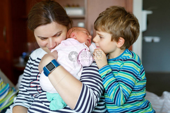 快乐的小男孩在医院亲吻他熟睡的新生小妹母亲手臂上抱着女婴兄弟姐妹们图片