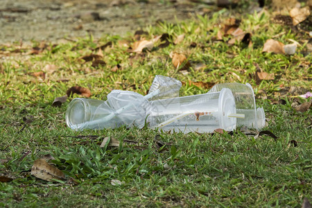 在公共园中不当处置不可生物降解的聚氯乙烯杯和稻草的图片