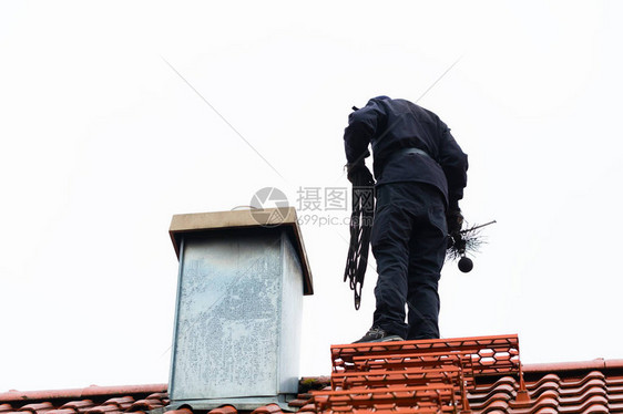 烟囱清扫站在家庭工作的屋顶上图片