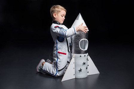 穿太空服的男孩航天员在火箭附近图片