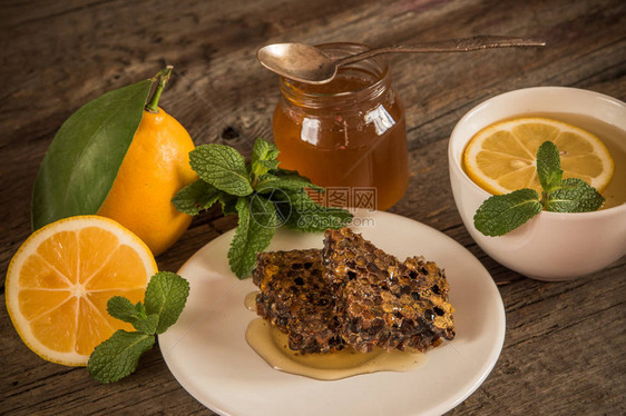 蜂窝罐子里的蜂蜜绿茶柠檬和叶子图片