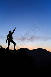 女徒步旅行者登山者或越野跑者在山顶上张开双臂图片