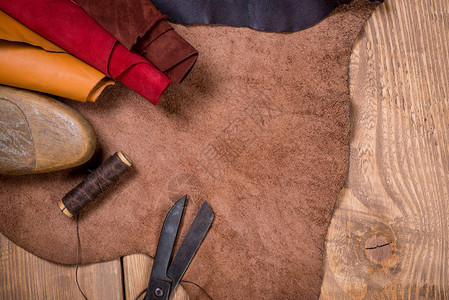 木制背景上的皮革工艺具集鞋匠的工作场所一块隐藏和工作桌图片