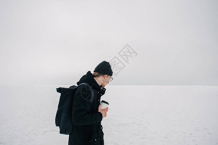 在冰冻的湖边带着一杯咖啡看着一片空虚身着黑色冬天穿黑衣图片