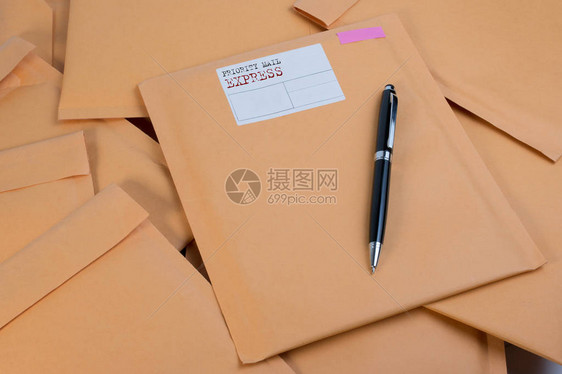 在木制桌子上堆放泡沫包装加盖的邮件信封和白色背景颜色的笔信封包装防图片